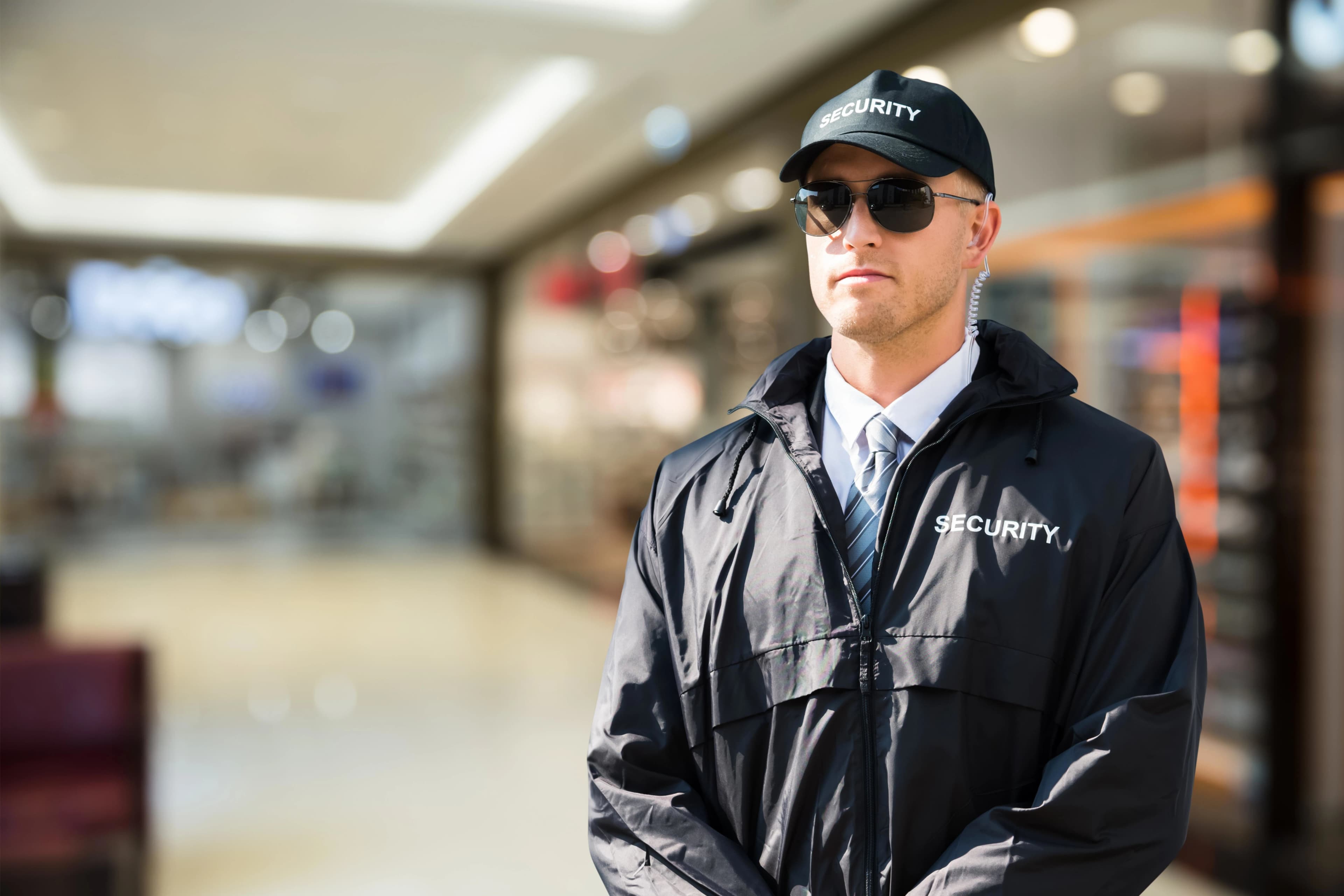 Security guard in branded uniform and cap patrolling a retail shopping centre in London