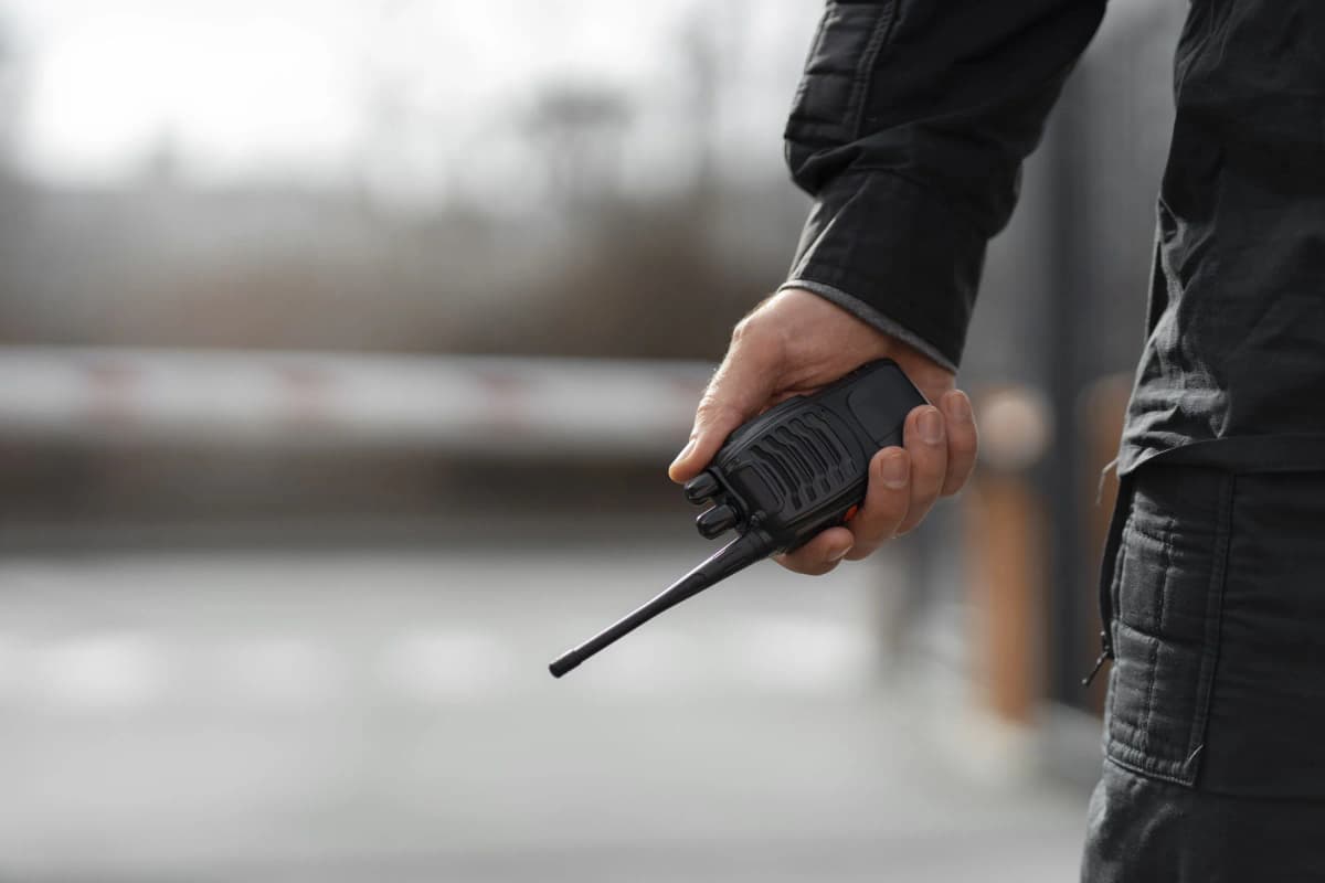Security officer holding two-way radio on patrol at outdoor entrance checkpoint in London
